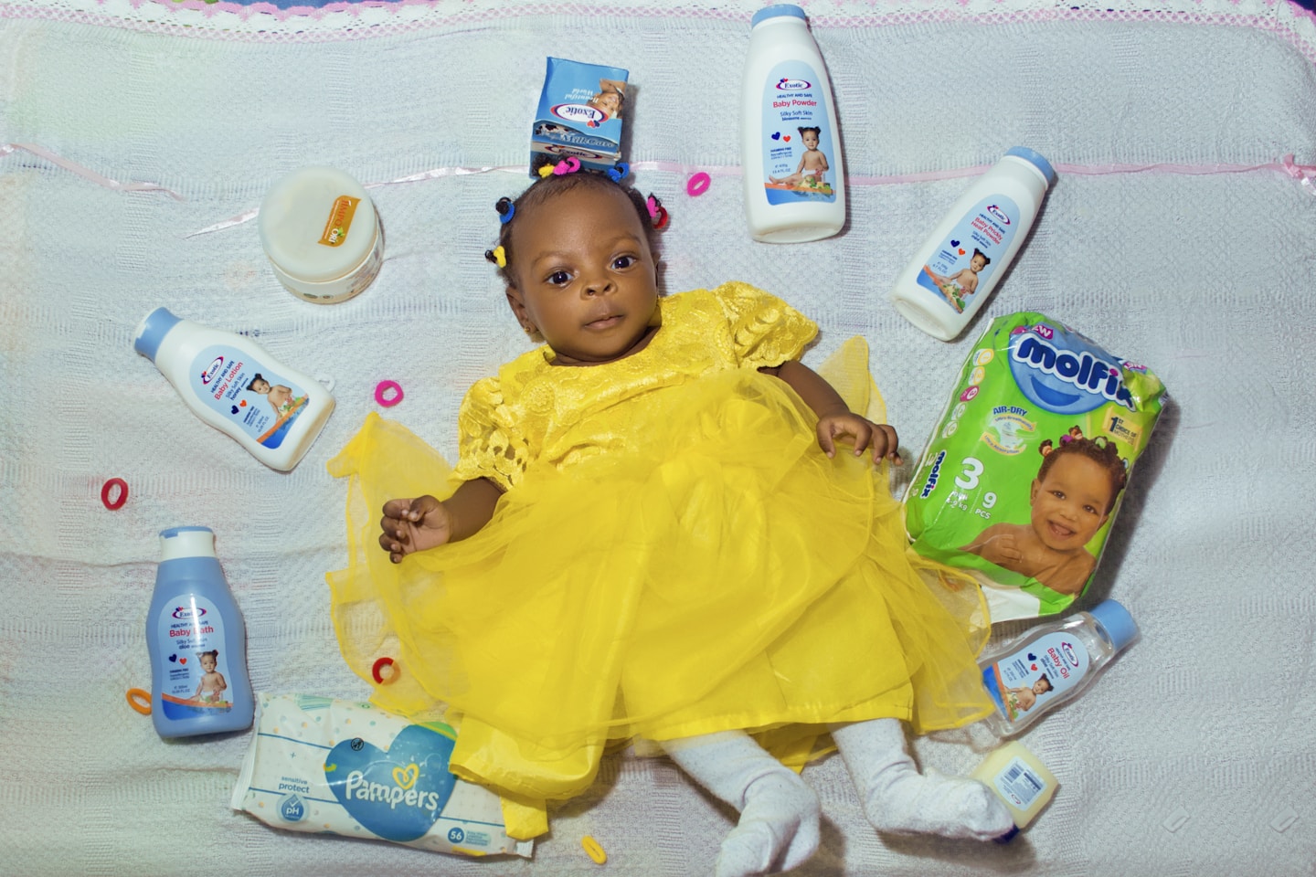 baby in yellow dress lying on bed
